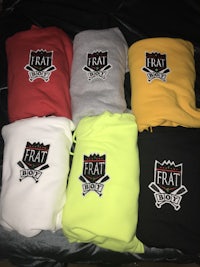 a group of different colored sweatshirts on a bed